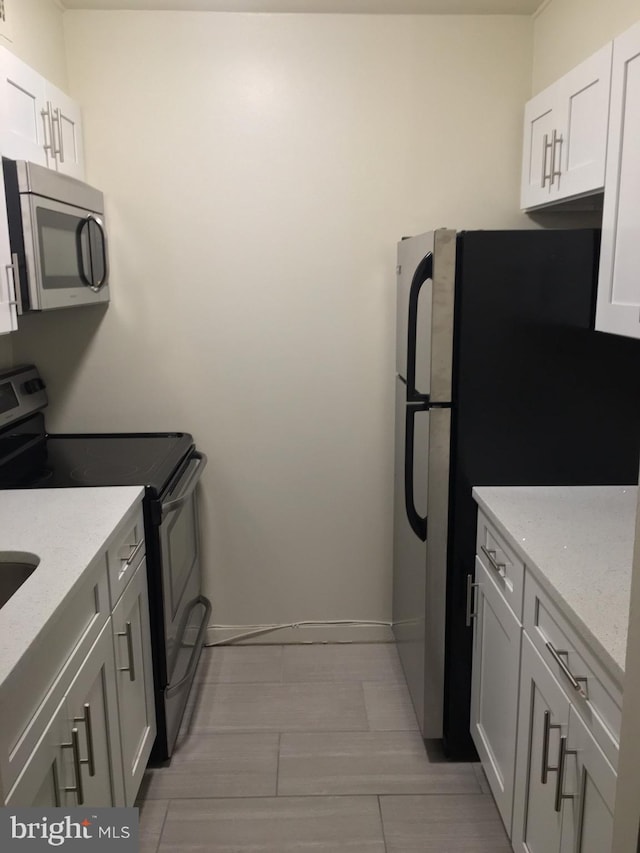 kitchen with light stone countertops, stainless steel appliances, and white cabinets