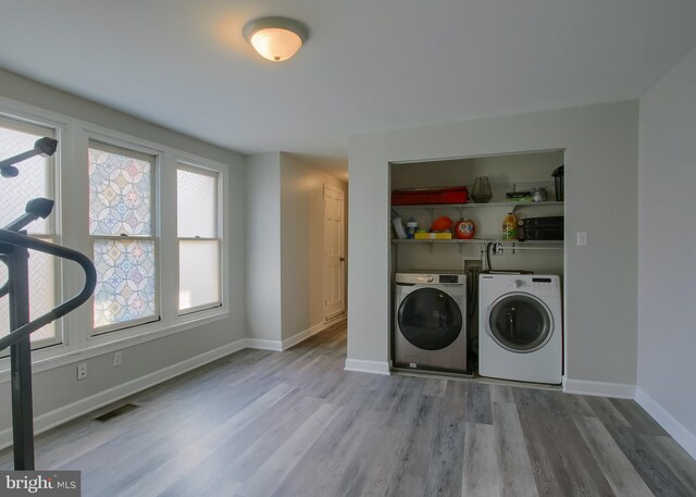 clothes washing area featuring light wood-type flooring and washer and dryer