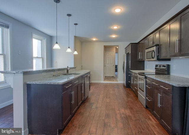 kitchen featuring stainless steel appliances, dark hardwood / wood-style flooring, hanging light fixtures, sink, and dark brown cabinets