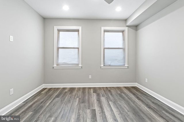 spare room with ceiling fan, a wealth of natural light, and dark hardwood / wood-style flooring