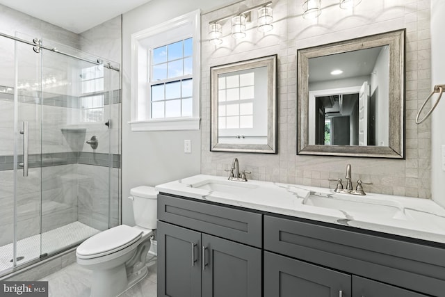 bathroom with a shower with shower door, toilet, and vanity