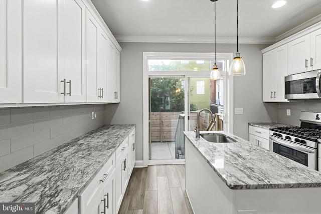 kitchen featuring white cabinets, a center island, light wood-type flooring, appliances with stainless steel finishes, and sink