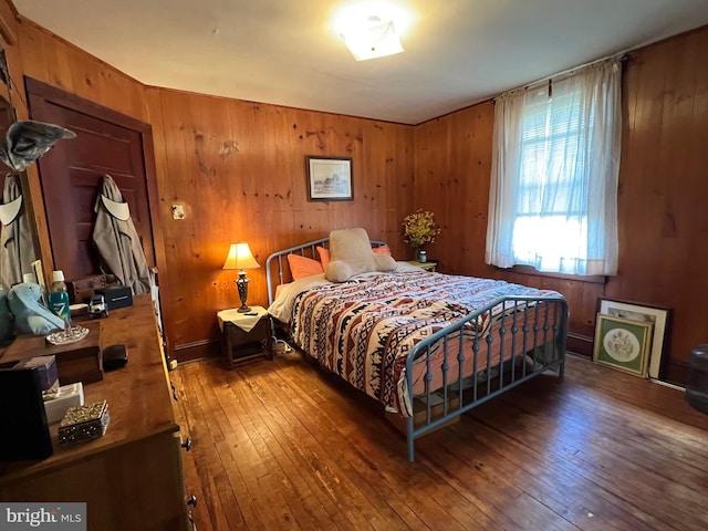 bedroom with hardwood / wood-style flooring and wood walls