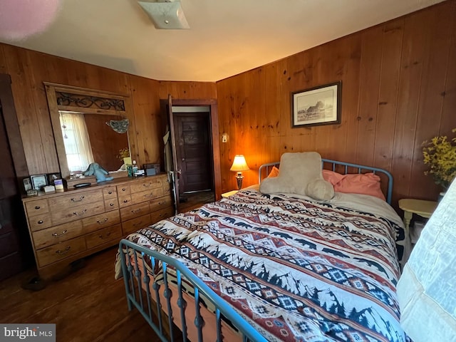 bedroom with wood walls and dark wood-type flooring