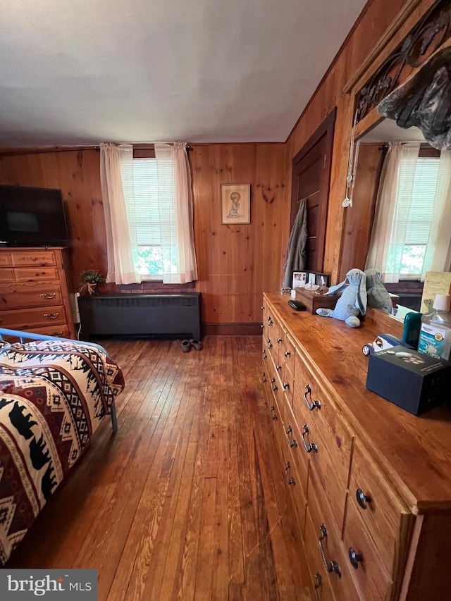 bedroom featuring multiple windows, wood walls, and dark hardwood / wood-style floors