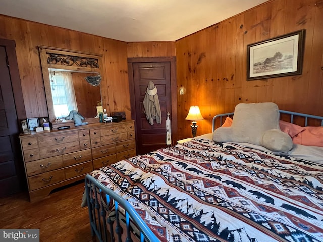 bedroom with dark wood-type flooring and wooden walls