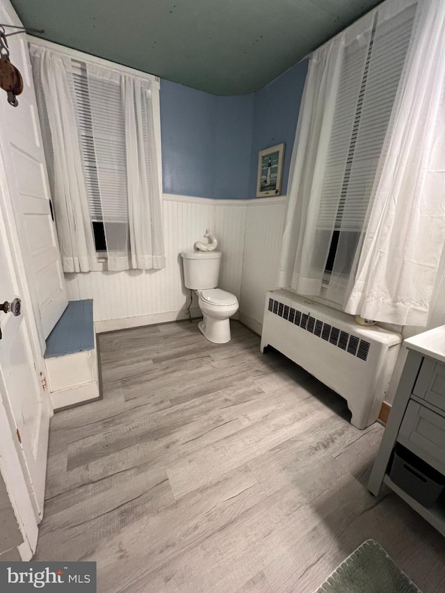 bathroom with wainscoting, toilet, radiator heating unit, wood finished floors, and vanity