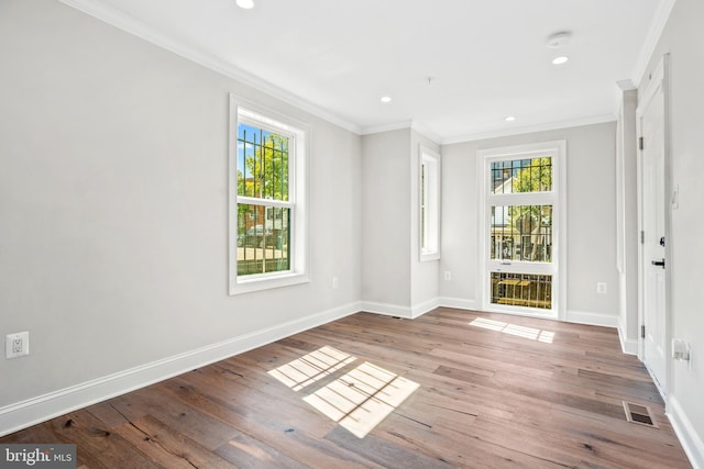 spare room with ornamental molding, plenty of natural light, and light hardwood / wood-style floors