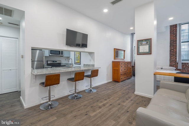 kitchen with stainless steel appliances, visible vents, a breakfast bar area, and wood finished floors