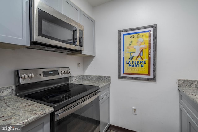 kitchen featuring stainless steel appliances, gray cabinets, and light stone countertops