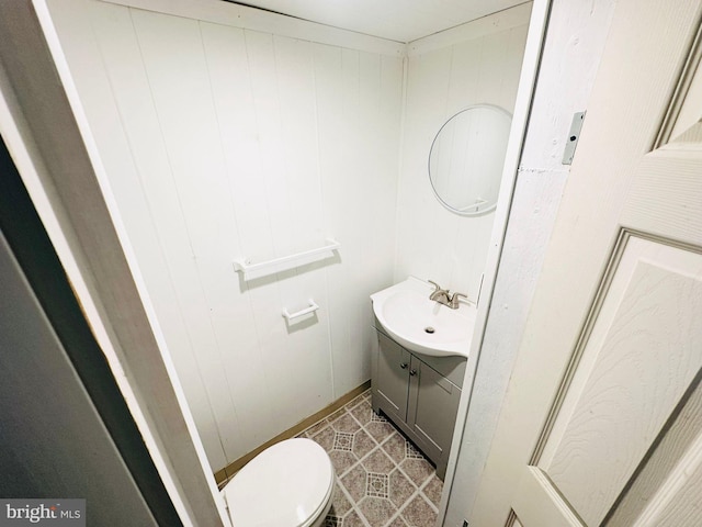 bathroom featuring vanity, toilet, tile patterned floors, and wooden walls