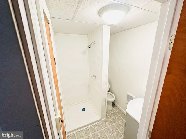 bathroom with vanity, tile patterned flooring, toilet, a shower, and a drop ceiling