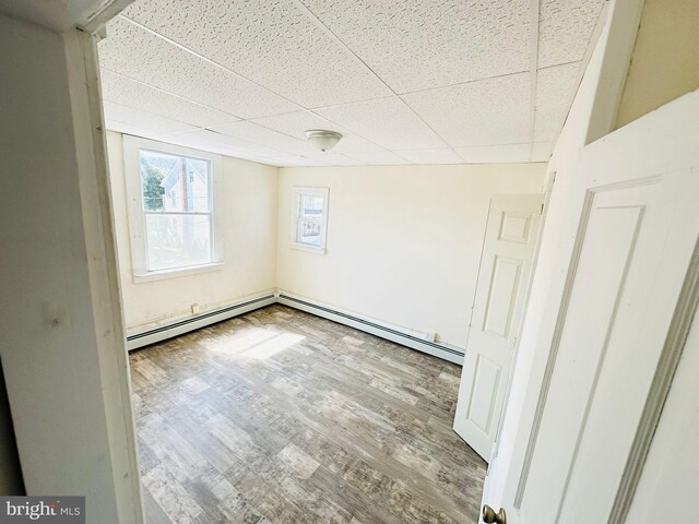 unfurnished room with a paneled ceiling, light hardwood / wood-style floors, and a baseboard heating unit