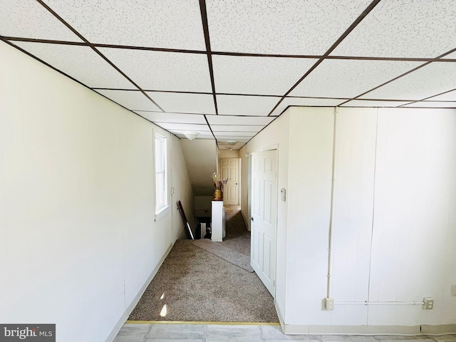 hall with a paneled ceiling and carpet