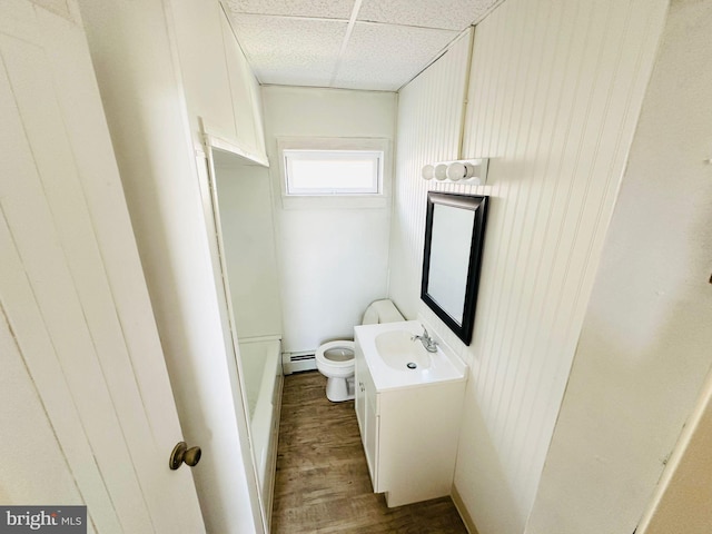 bathroom featuring toilet, hardwood / wood-style floors, vanity, a paneled ceiling, and a baseboard heating unit