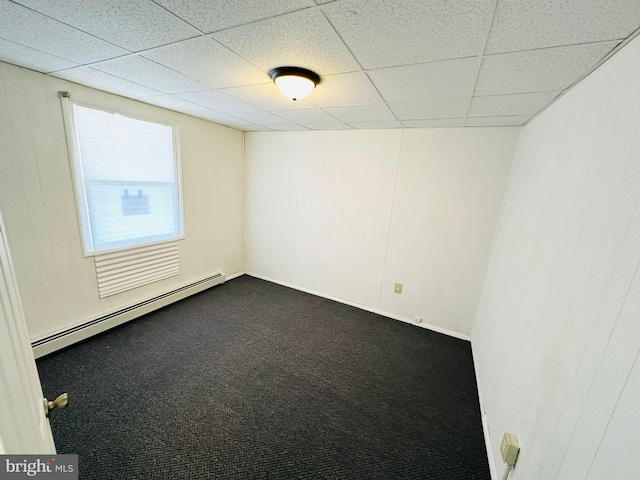 carpeted empty room with baseboard heating and a drop ceiling