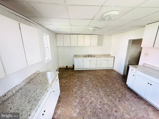 kitchen with a paneled ceiling, sink, and white cabinets