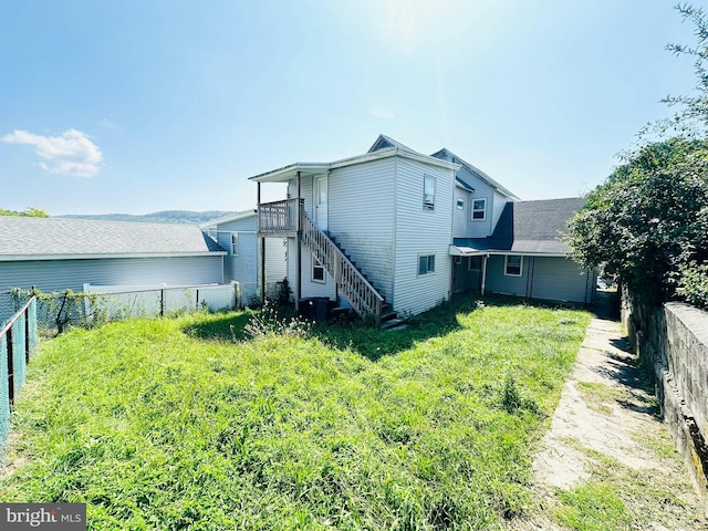 back of house featuring stairs, a yard, and a fenced backyard