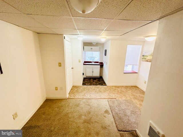 hallway featuring a paneled ceiling, carpet, and sink