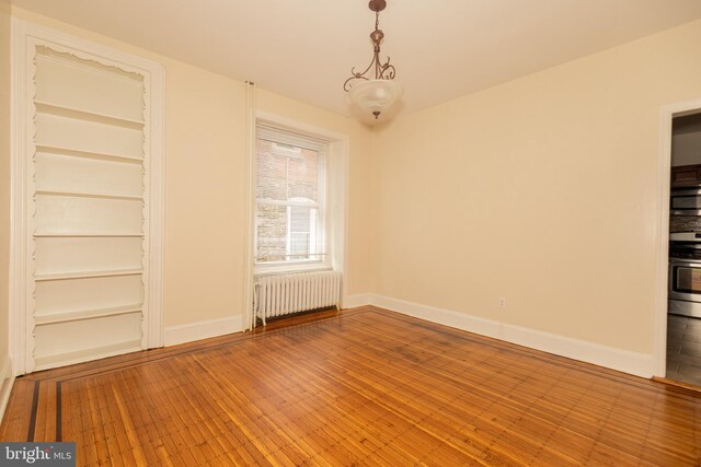 interior space featuring built in shelves, radiator, and hardwood / wood-style flooring