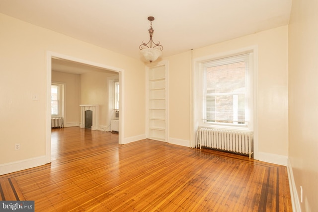 spare room featuring wood-type flooring, plenty of natural light, and radiator heating unit