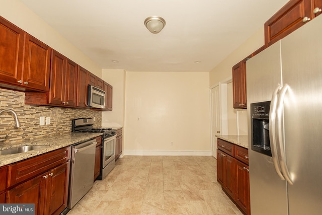 kitchen featuring sink, light stone countertops, appliances with stainless steel finishes, and tasteful backsplash