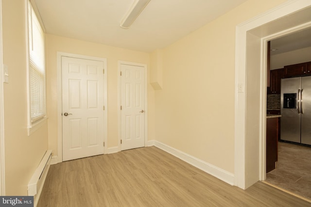 empty room featuring light wood-type flooring and a baseboard radiator