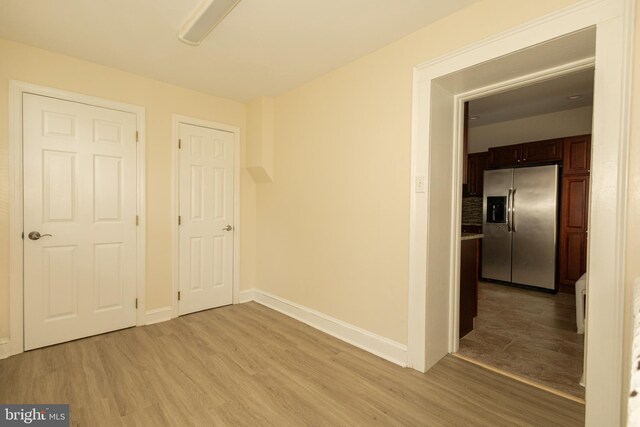 unfurnished bedroom featuring stainless steel fridge with ice dispenser, light hardwood / wood-style flooring, and ceiling fan