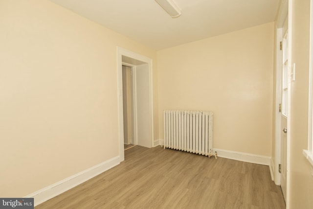 spare room featuring radiator and light wood-type flooring