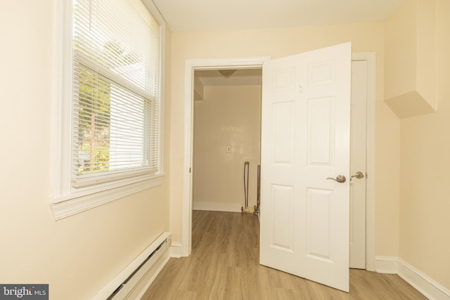 hall featuring a baseboard heating unit and light wood-type flooring