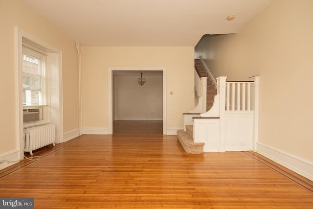 interior space with radiator, light wood-style flooring, baseboards, and stairs