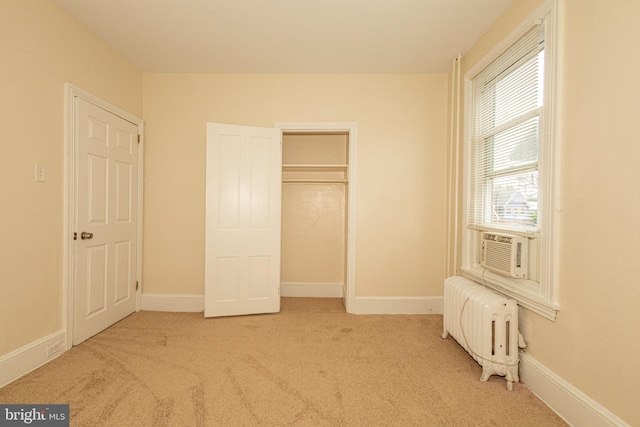 unfurnished bedroom with a closet, light colored carpet, and radiator