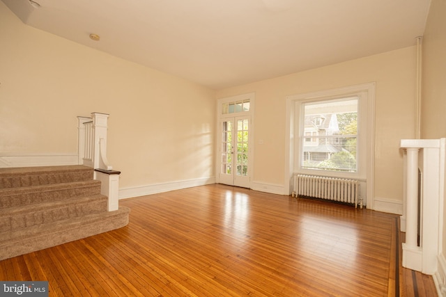 unfurnished living room with radiator and wood-type flooring