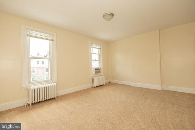 carpeted empty room with radiator heating unit and plenty of natural light