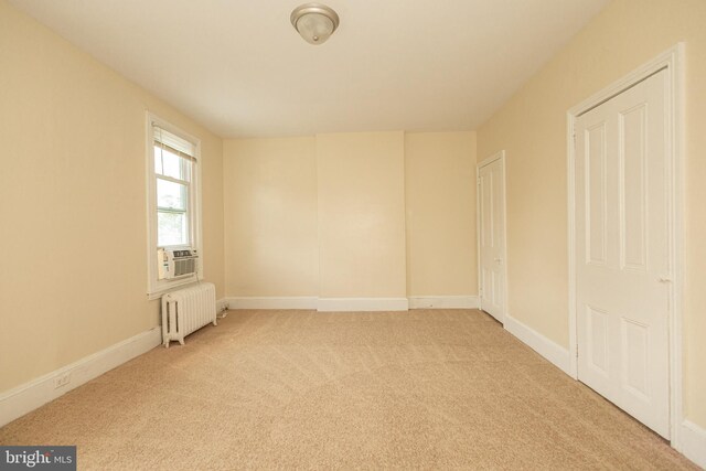 carpeted empty room featuring radiator heating unit