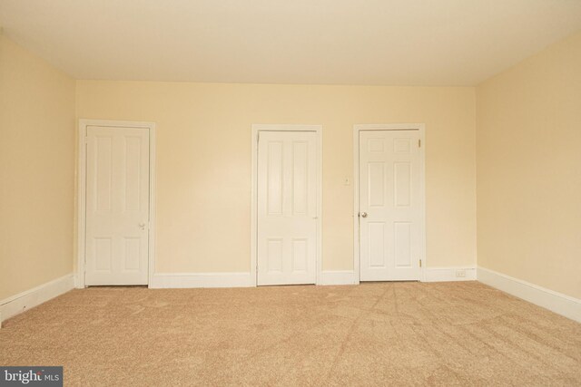 unfurnished bedroom with two closets and light carpet