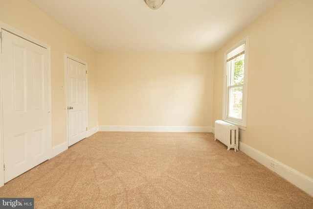 unfurnished bedroom featuring light colored carpet and radiator