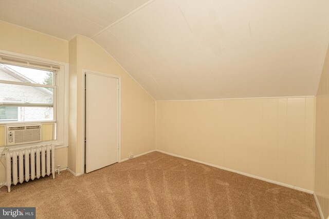 additional living space with lofted ceiling, light colored carpet, cooling unit, and radiator heating unit