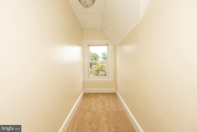 corridor with vaulted ceiling and light colored carpet