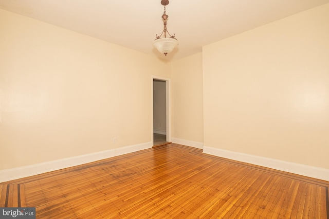 spare room with hardwood / wood-style flooring and an inviting chandelier