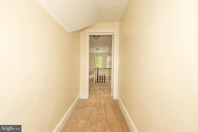 corridor featuring lofted ceiling and light carpet