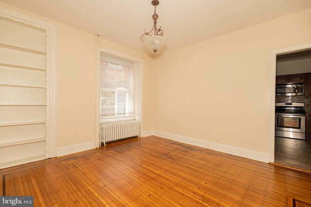 spare room featuring radiator heating unit and light hardwood / wood-style flooring