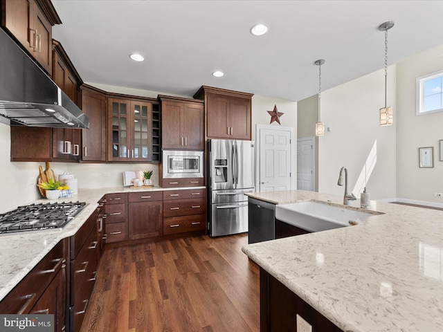 kitchen featuring appliances with stainless steel finishes, light stone counters, sink, dark wood-type flooring, and pendant lighting