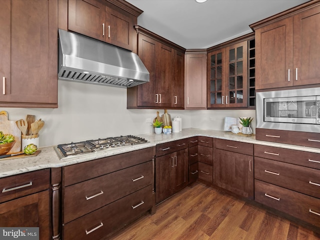 kitchen featuring stainless steel appliances, light stone countertops, dark hardwood / wood-style flooring, and dark brown cabinetry