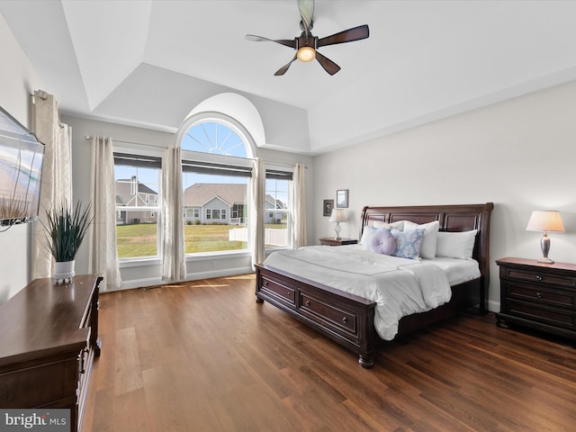 bedroom with dark wood-type flooring, a raised ceiling, and ceiling fan