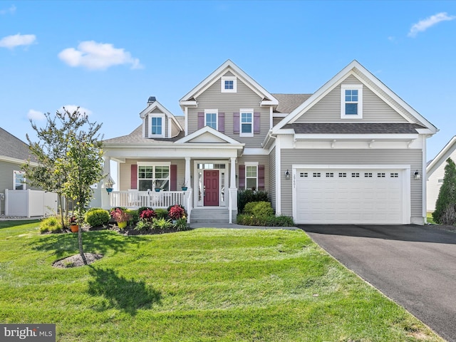 view of front facade with a front lawn, driveway, a porch, fence, and a shingled roof