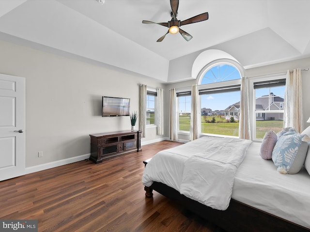 bedroom featuring dark wood-type flooring, multiple windows, ceiling fan, and a raised ceiling