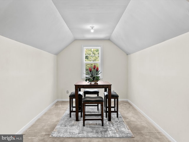 dining area with light colored carpet and vaulted ceiling