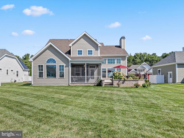 back of house featuring a yard and a sunroom