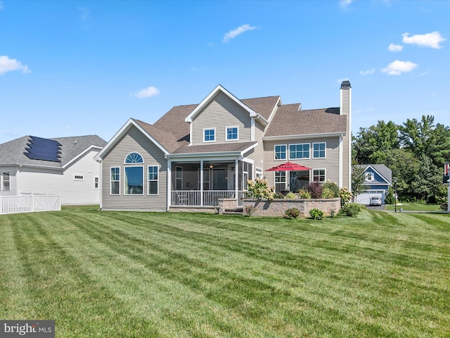 back of property featuring a garage, a sunroom, and a lawn